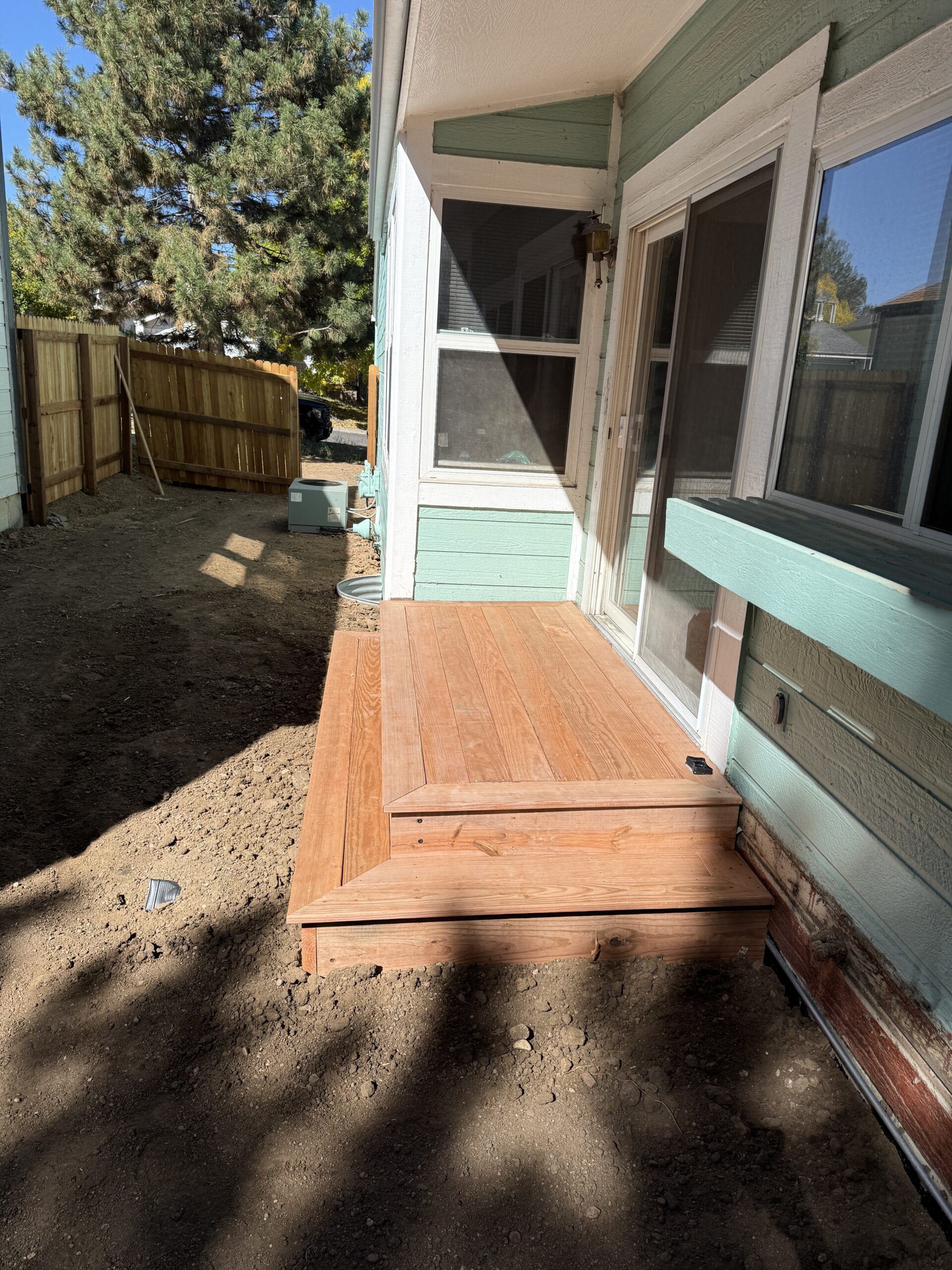 White house by a stream with a view of a forested hill.