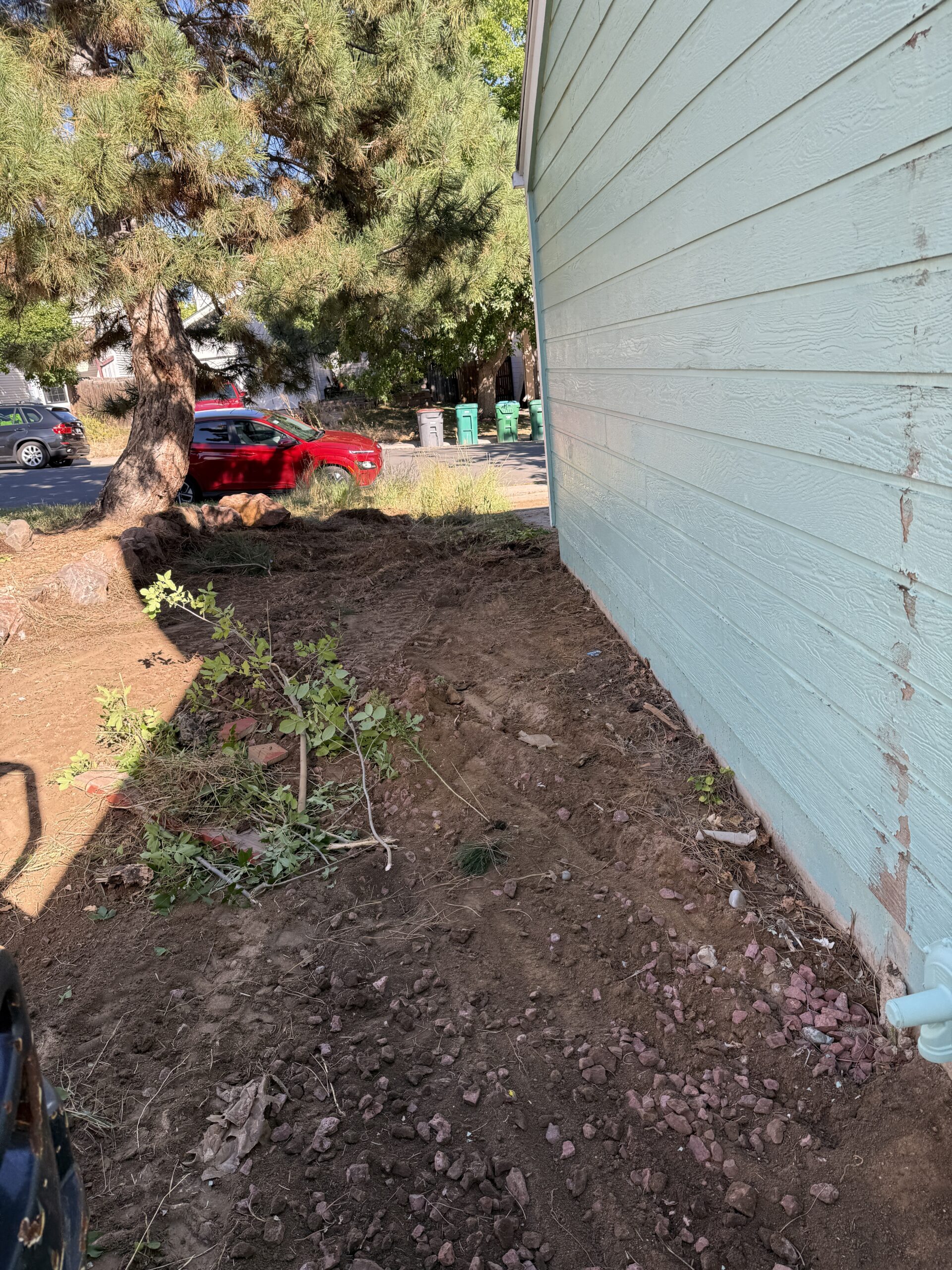 White house by a stream with a view of a forested hill.