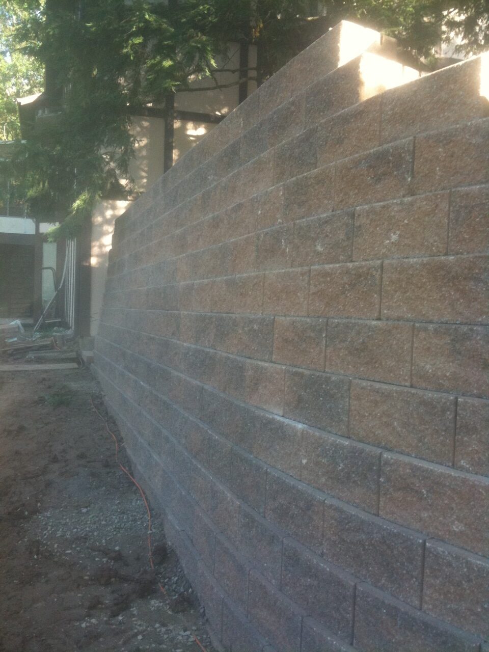 White house by a stream with a view of a forested hill.