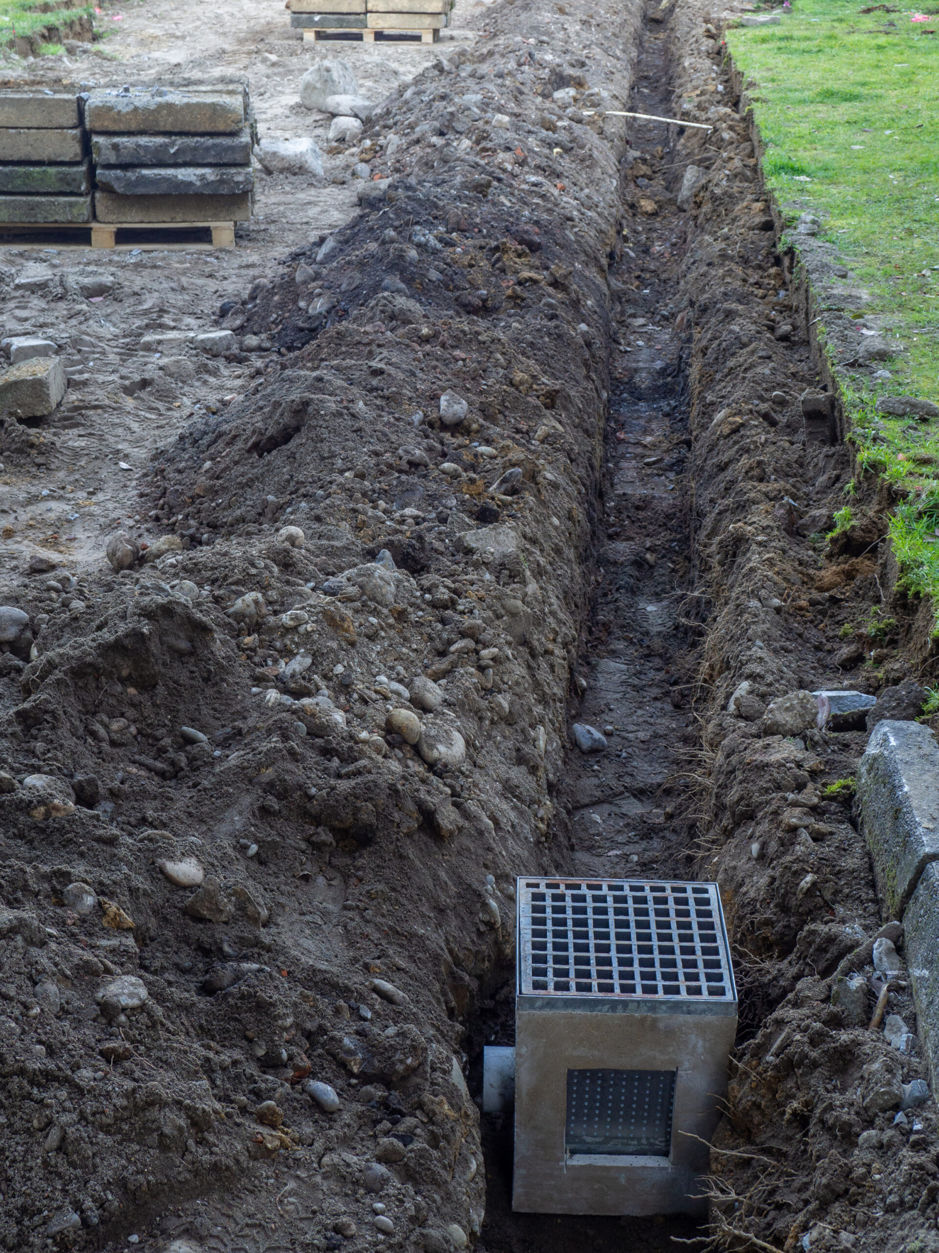 White house by a stream with a view of a forested hill.